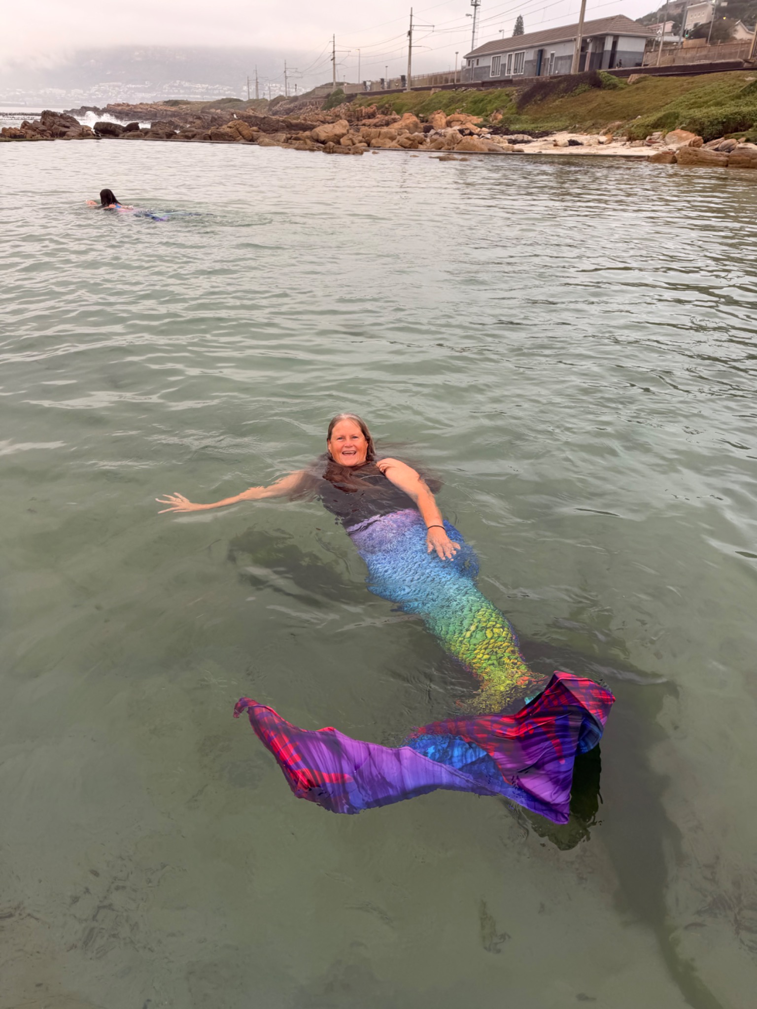 Smiling mermaid floating peacefully in shallow tidal water