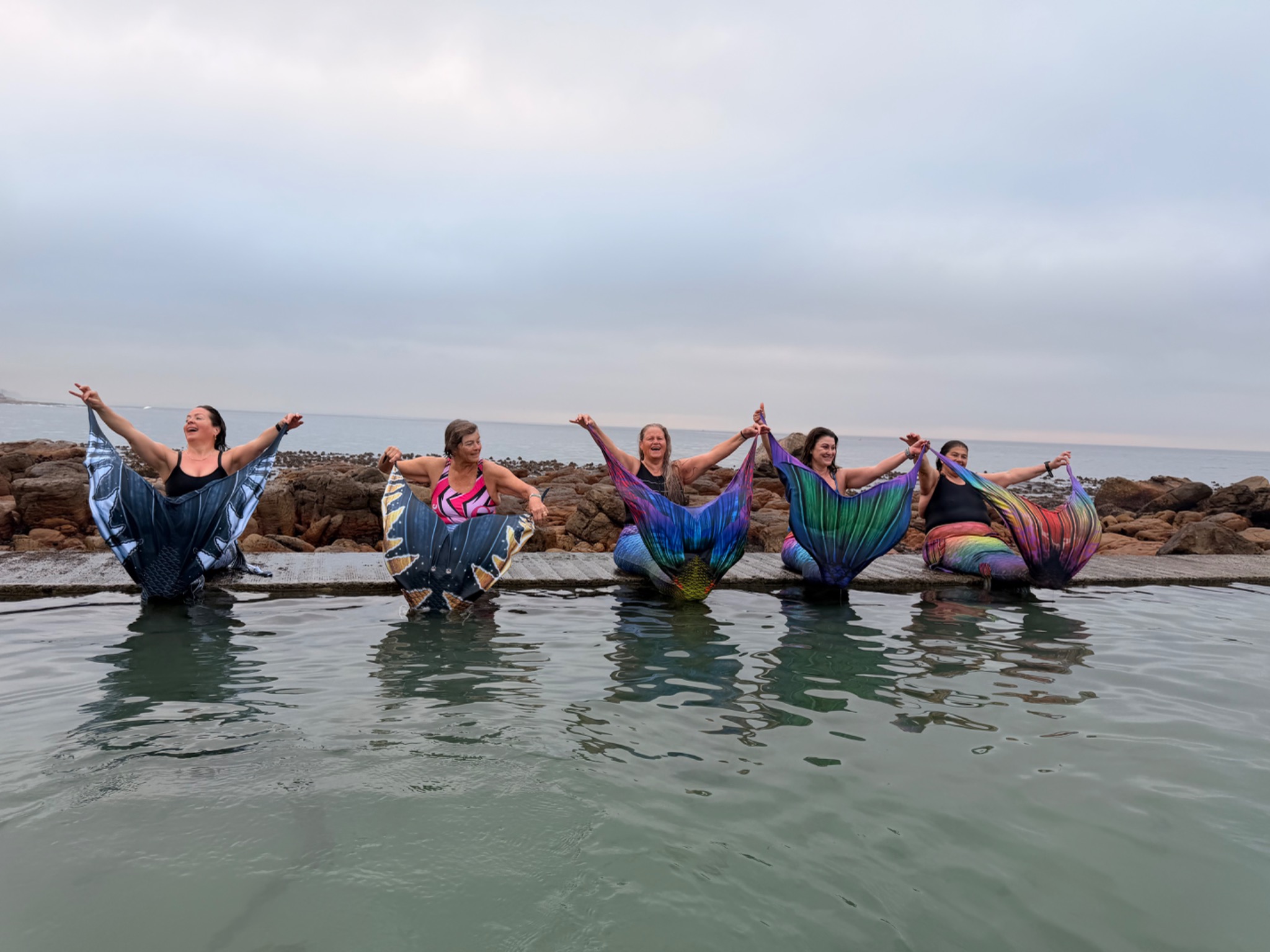 Mermaid friends smiling and celebrating in the tidal pool