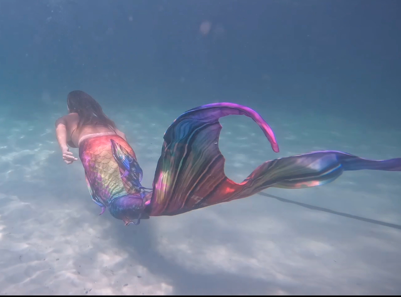 Mermaid with a colourful tail beside the pool