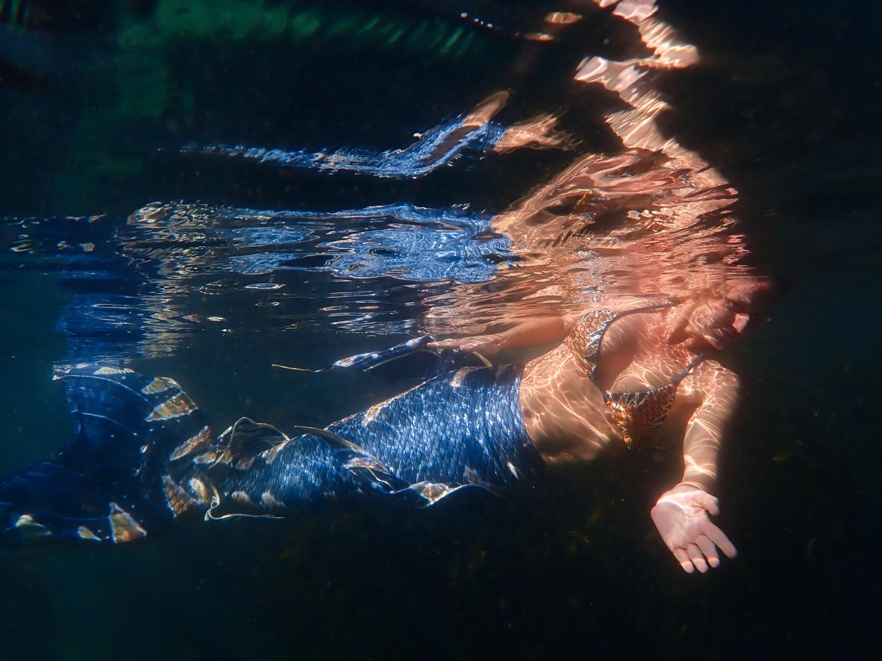Mermaid floating beneath shimmering surface light